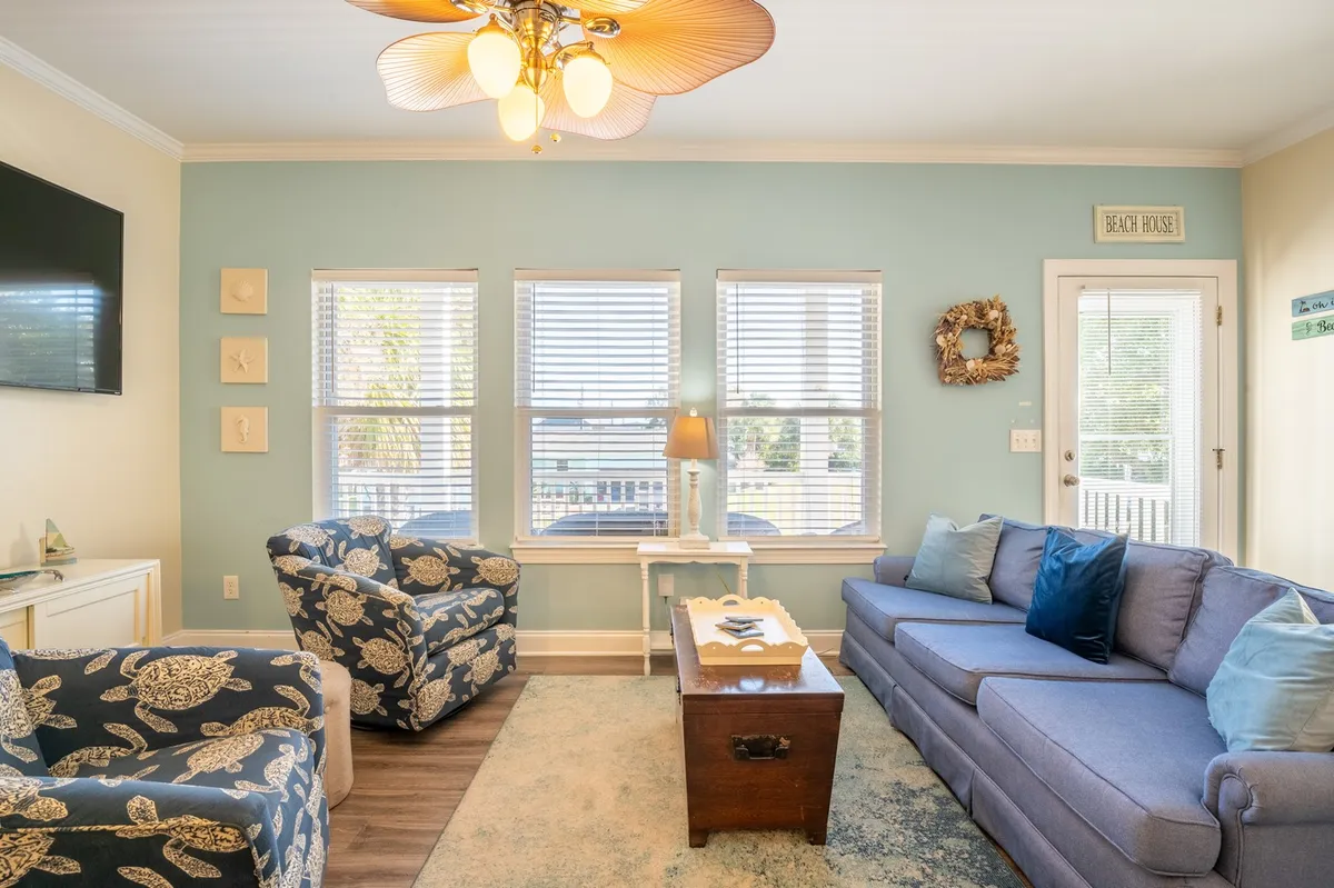 This image features a sunlit living space with a blue sofa, decorative armchairs, and a coffee table, all bathed in natural light from a large window. The openness and comfort of the room reinforce the idea of a welcoming retreat after a day of exploring the local scene.