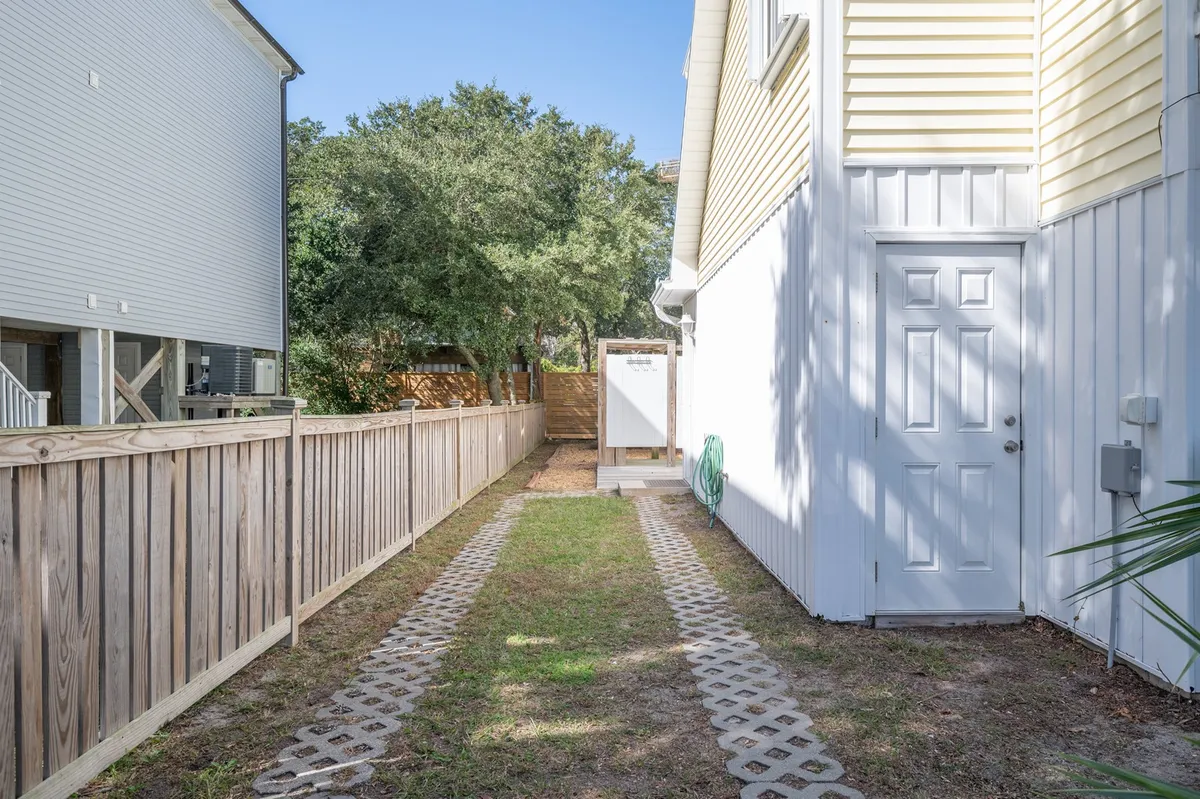 This image presents the home's exterior, with a welcoming pathway leading to the door, lush green foliage, and a visible fence line. The surroundings feel calm and serene, suggesting a peaceful neighborhood ideal for morning dog walks.