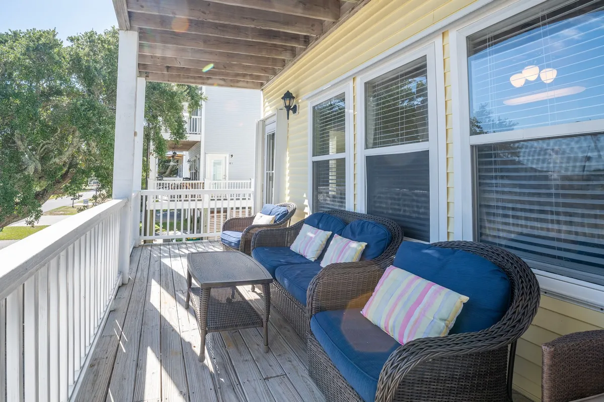 An outdoor patio furnished with wicker sofas featuring striped cushions and a wooden table, all set up for relaxation or socializing. The area is bathed in natural light, suggesting the ideal spot for casual meals or enjoying an afternoon breeze.
