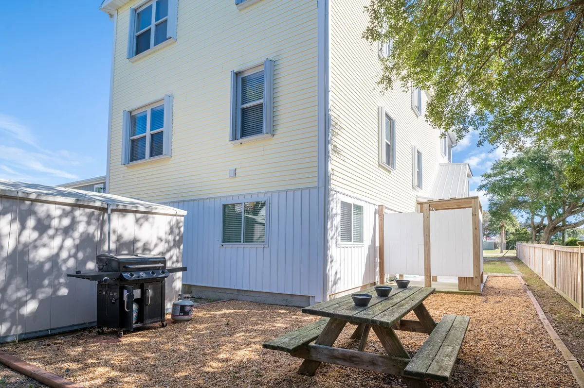 Showcasing an inviting backyard area featuring a grill, picnic table, and an outdoor privacy screen. The space is tailored for outdoor dining, social gatherings, and casual relaxation, capturing the atmosphere of returning home from an adventure.
