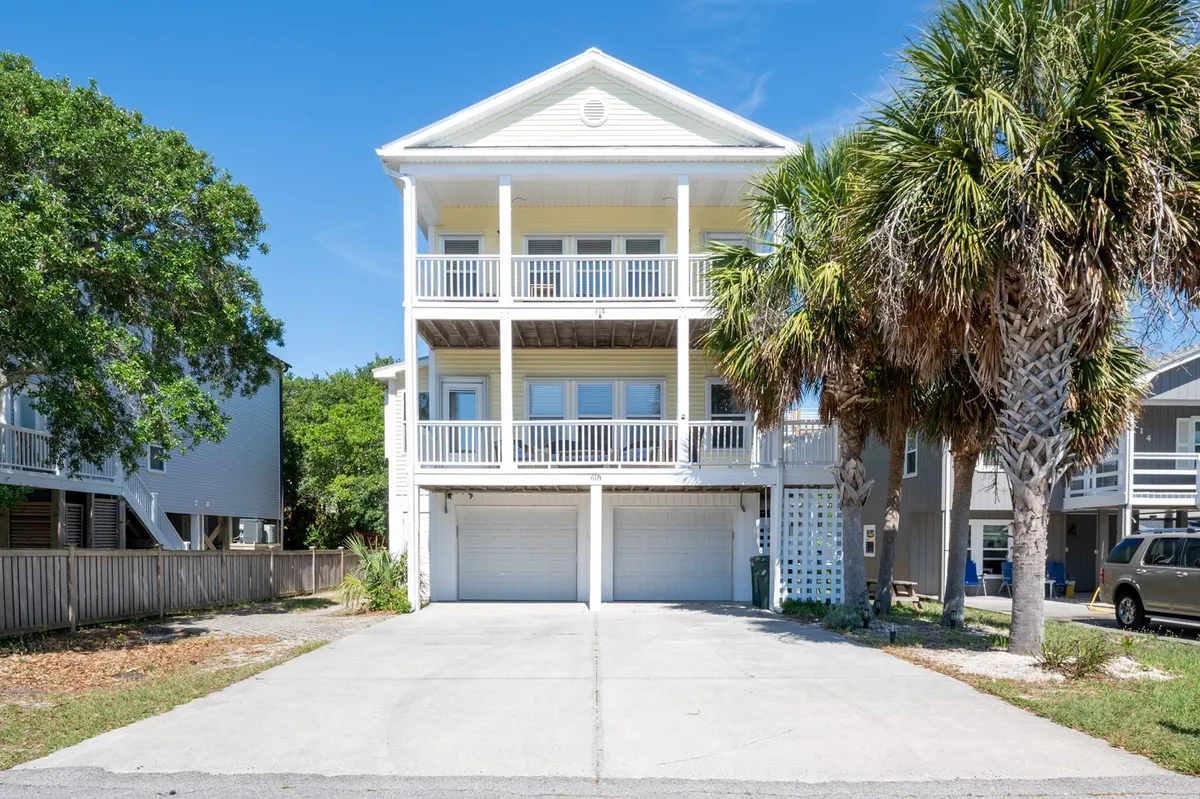 The image showcases a cheerful two-story duplex surrounded by swaying palm trees, with spacious balconies perfect for relaxing, a welcoming driveway, and hints of vibrant coastal life. The inviting outdoor spaces suggest plenty of room for gatherings, sunset views, and al fresco dining.