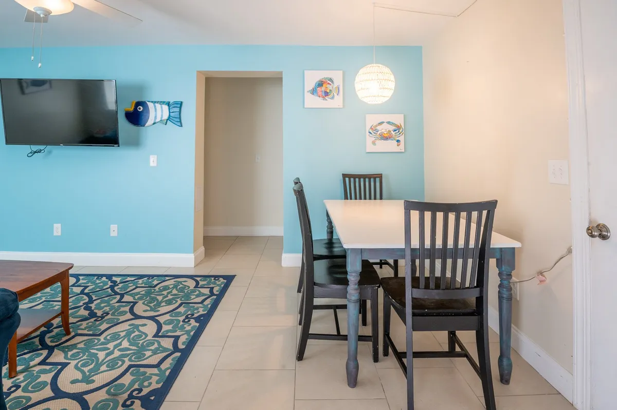 This image focuses on the spacious dining table, cheerful wall decor, and television in the background. The setup invites guests to enjoy family meals, casual gatherings, or cozy movie nights, reinforcing the social and communal atmosphere described in the section.