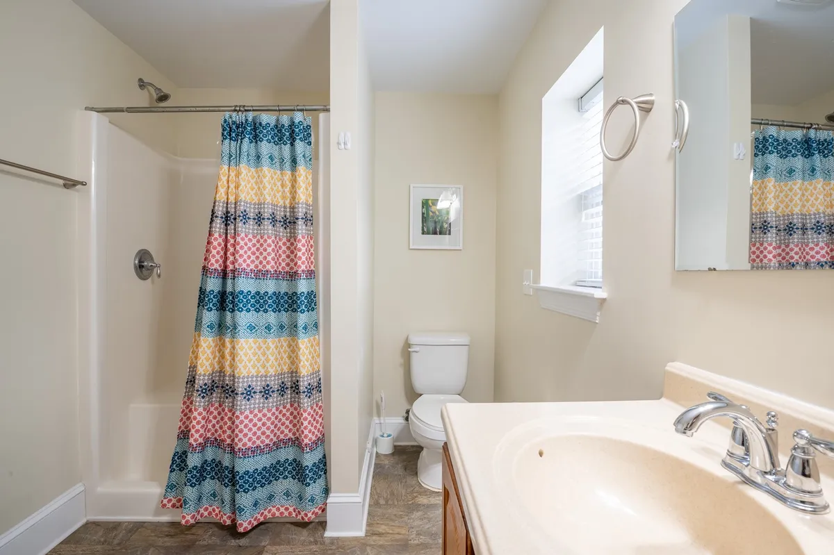A cheerful bathroom scene with a colorful shower curtain, a bright sink area, and a toilet. The room is vibrant and welcoming, ideal for refreshing after a day at the beach or getting ready for a new adventure.